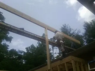 Carpenter setting a ridge beam over a new addition frame — Ice Dam Removal by Roofing Brothers in Big Piney