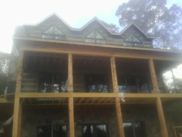Dormers and porch framing on a large log home under construction — Roof Coating work by our crew in Big Piney