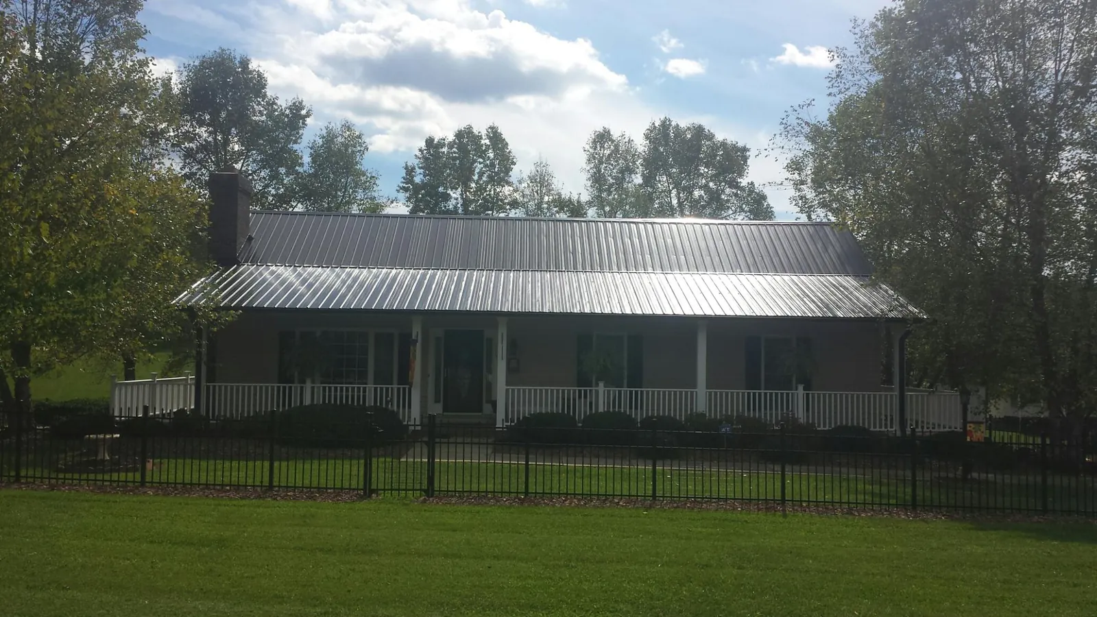 Gray metal roof on a brick ranch with a full width front porch — Gutter Guard Installation work by our crew in Big Piney