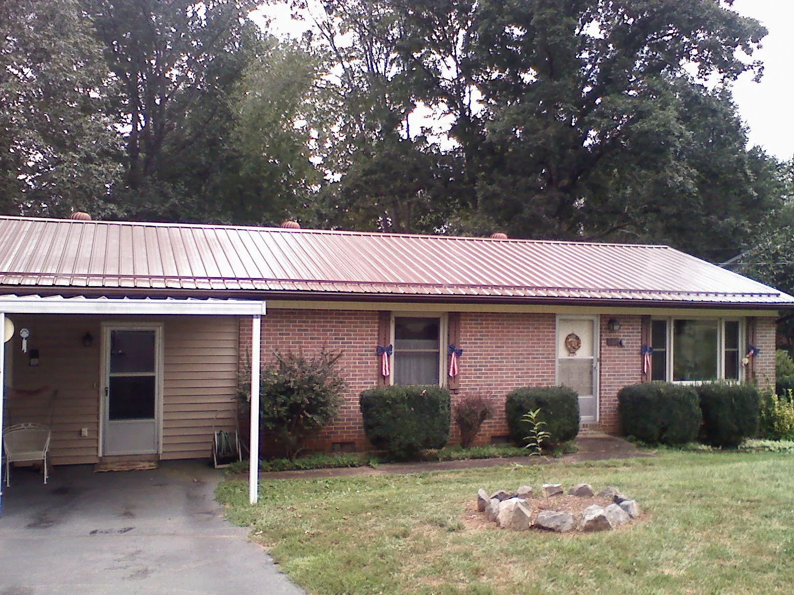 Bronze metal roof and carport on a brick ranch home — Roof Repair work by our crew in Big Piney