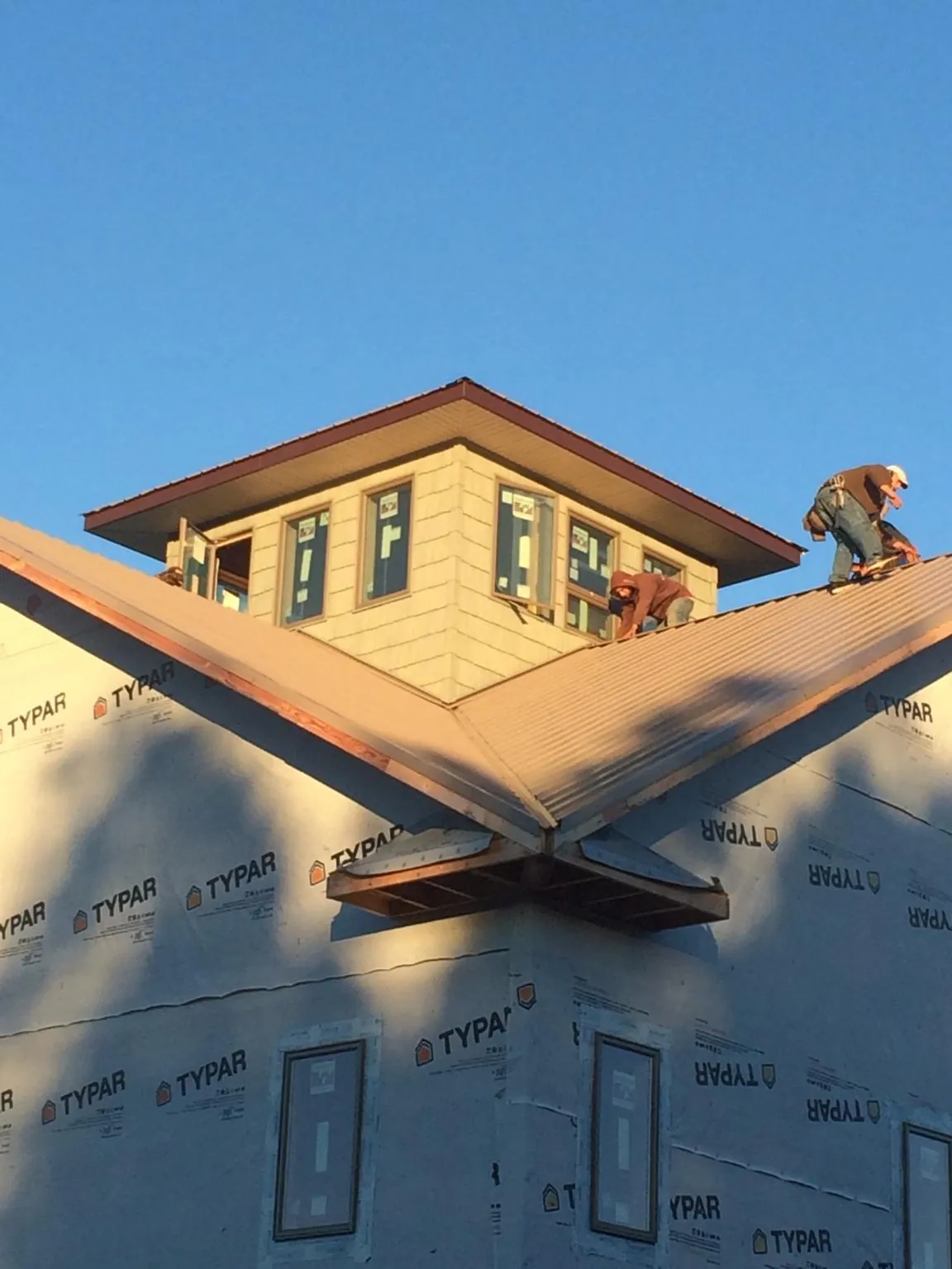 Roofers working around a rooftop cupola on a new metal roof at sunset — Roof Waterproofing in Big Piney by Roofing Brothers